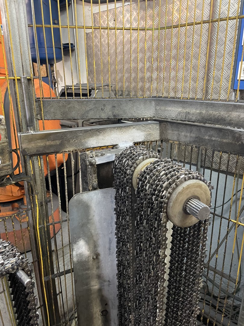 Mehrere Motorsägenketten, die über eine Rolle auf einer Antriebswelle in der Werkstatt hängen